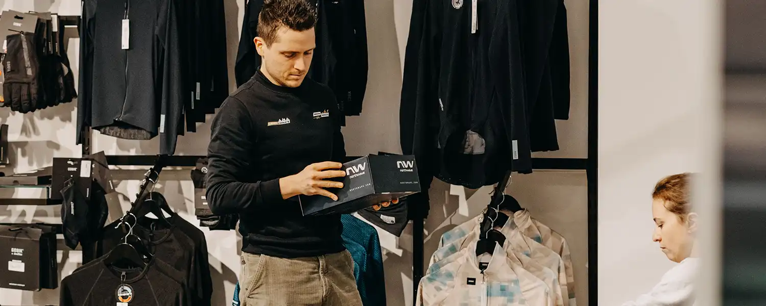 Medewerker van Iron Bikes met fietskleding en schoenen in de winkel